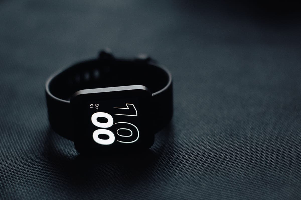 A square smartwatch showing the time on a dark surface