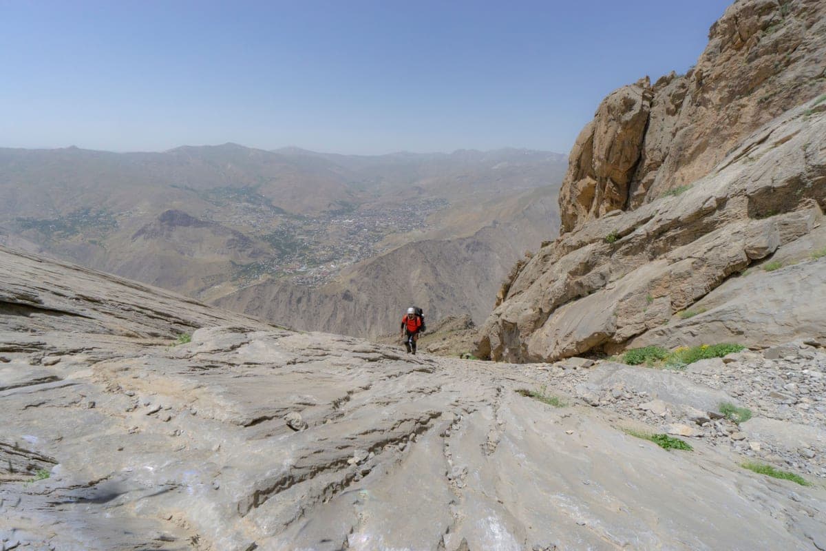 A hiker walking across rocky mountain terrain