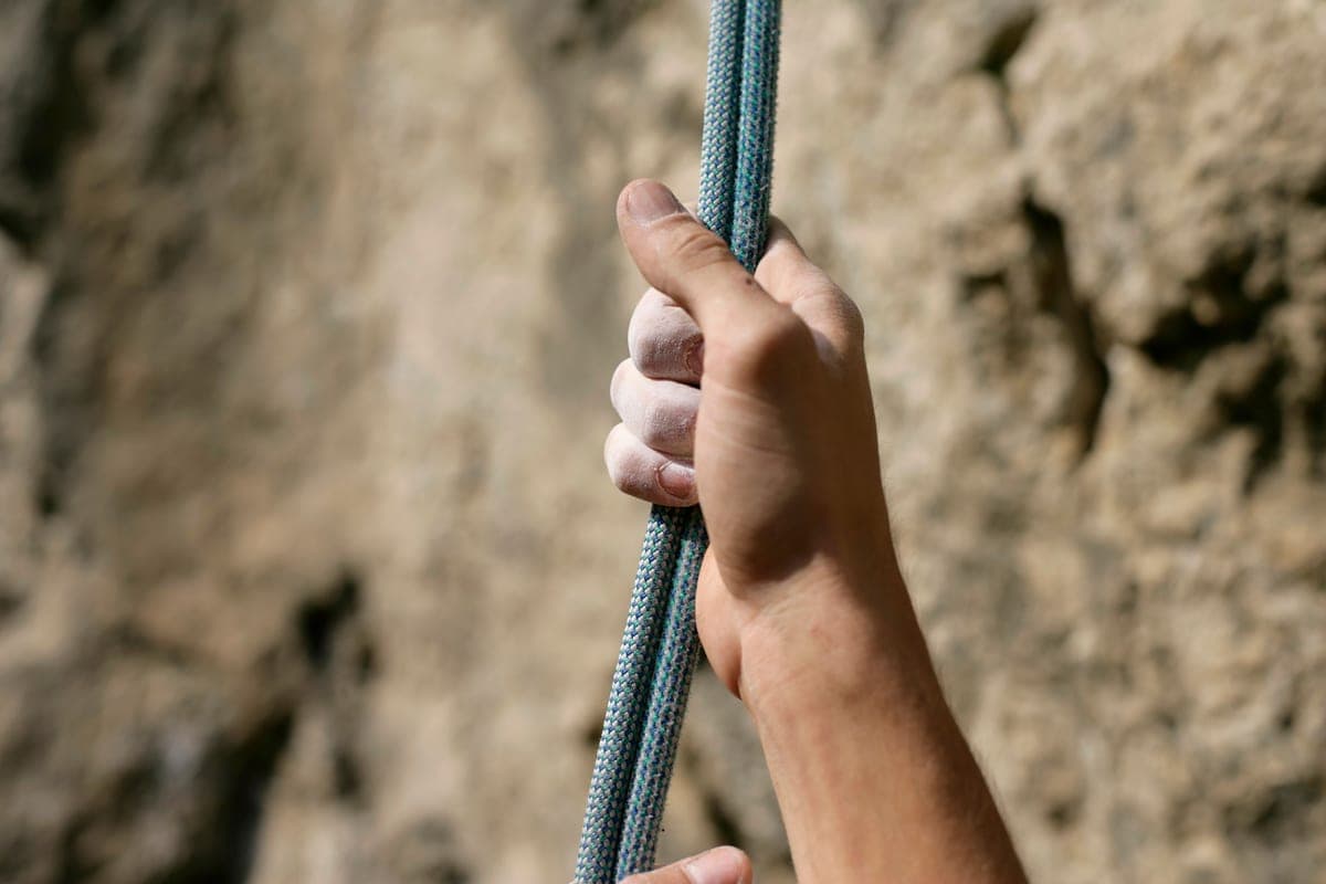 A hand gripping a rope against rock