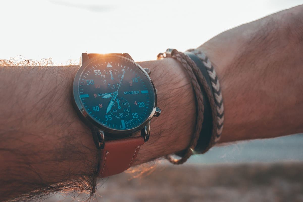 An analog watch on a wrist lit by low sun