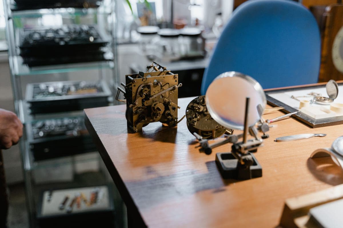 A watch repair bench with loupes, tweezers and a watch movement